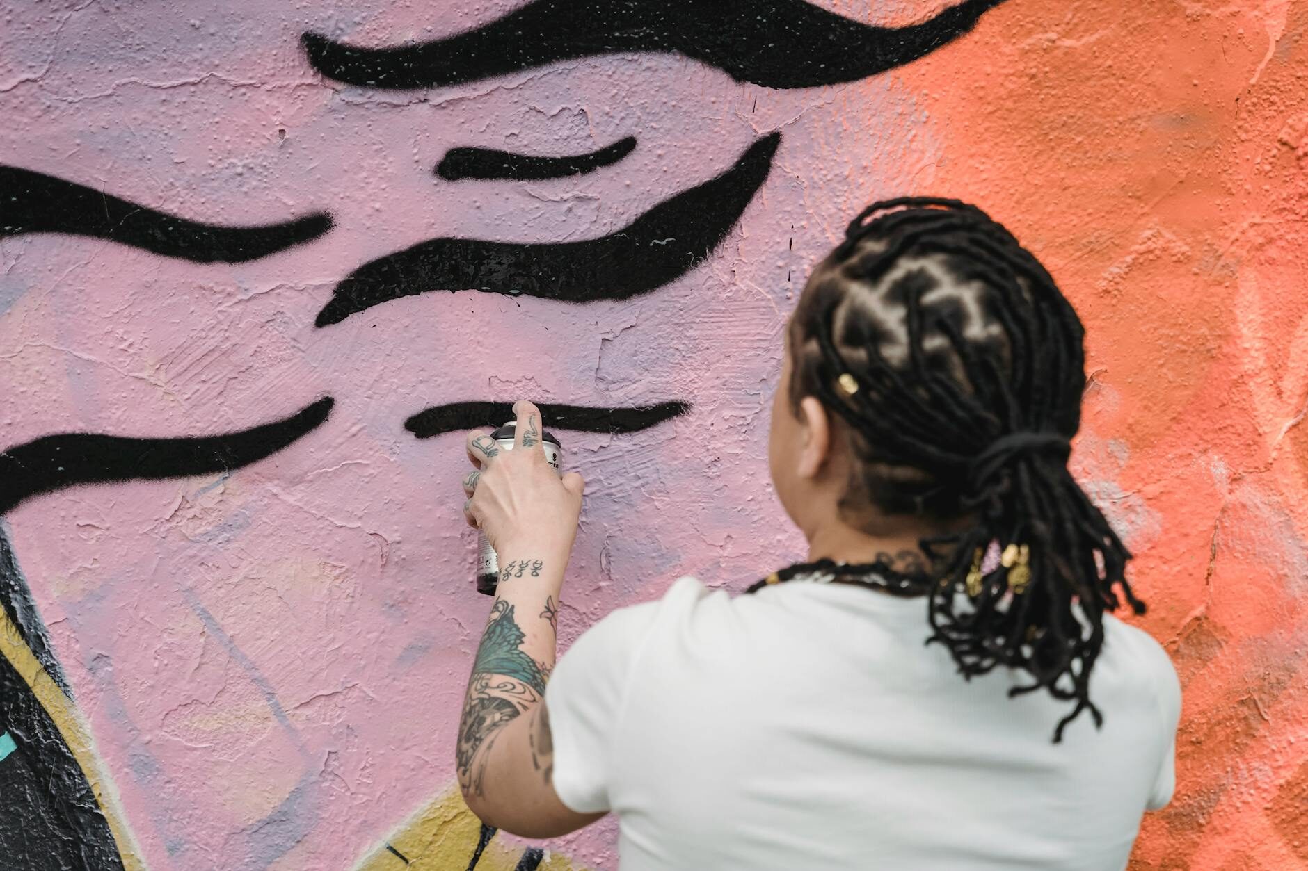 Mural artist working fine detail on a large warm-toned wall painting